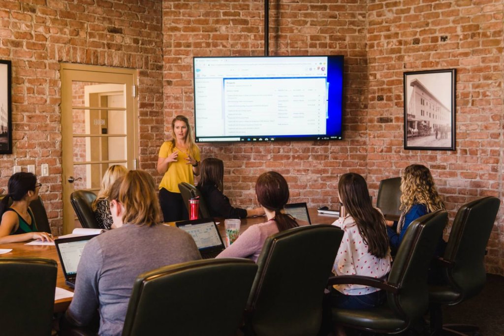 A woman leads a business meeting in a room with exposed brick walls