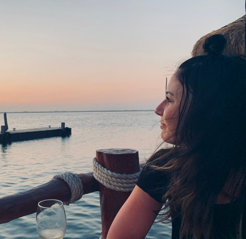 A woman looks out at the ocean during a peaceful sunset