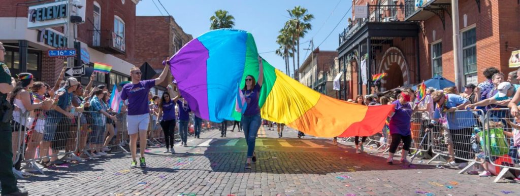 People carry a large rainbow flag down a city street during a pride parade