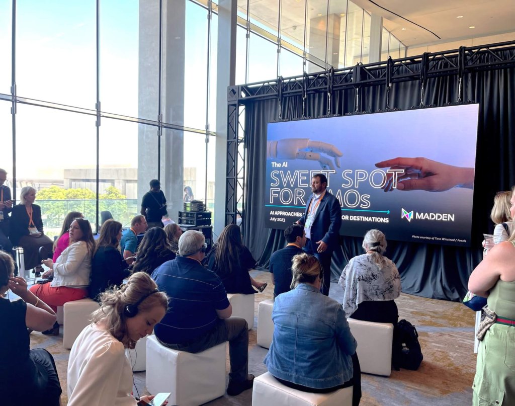 A man gives a presentation about AI to an audience in a bright room