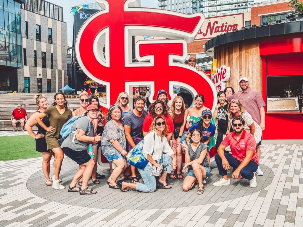 A large group of people posing for a photo in front of a red logo