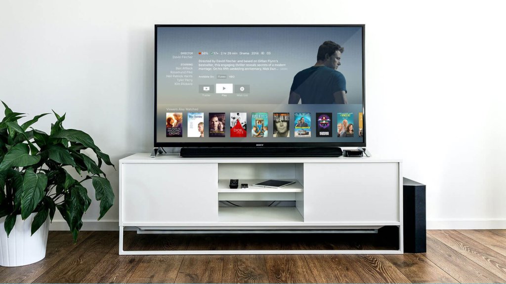A television displaying a movie streaming interface on a white media console