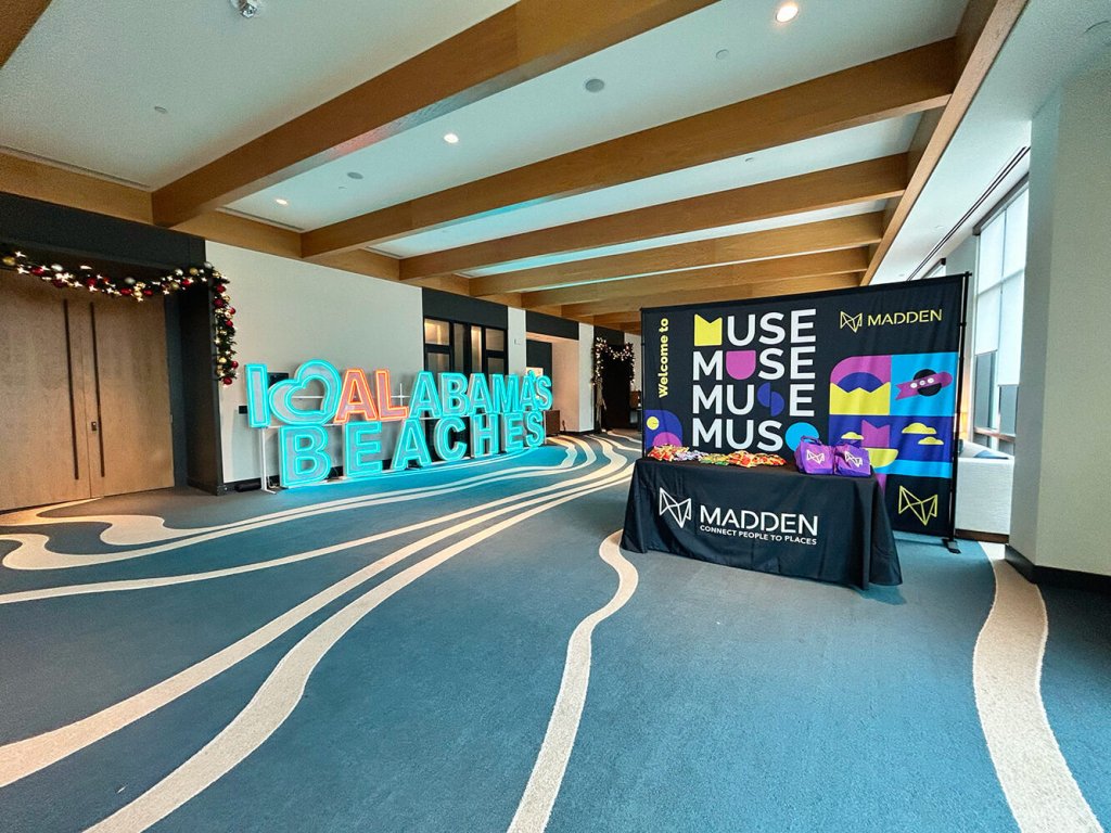 A conference room with a neon Alabama Beaches sign and a Madden branded display table