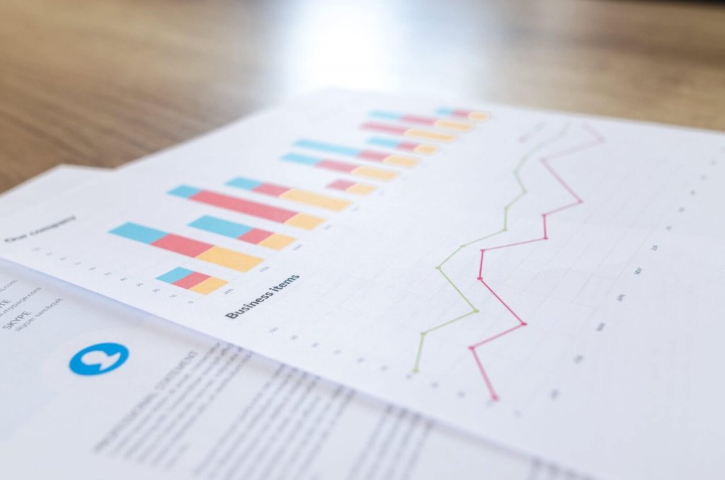 A printed business report with colorful bar and line charts on a wooden desk