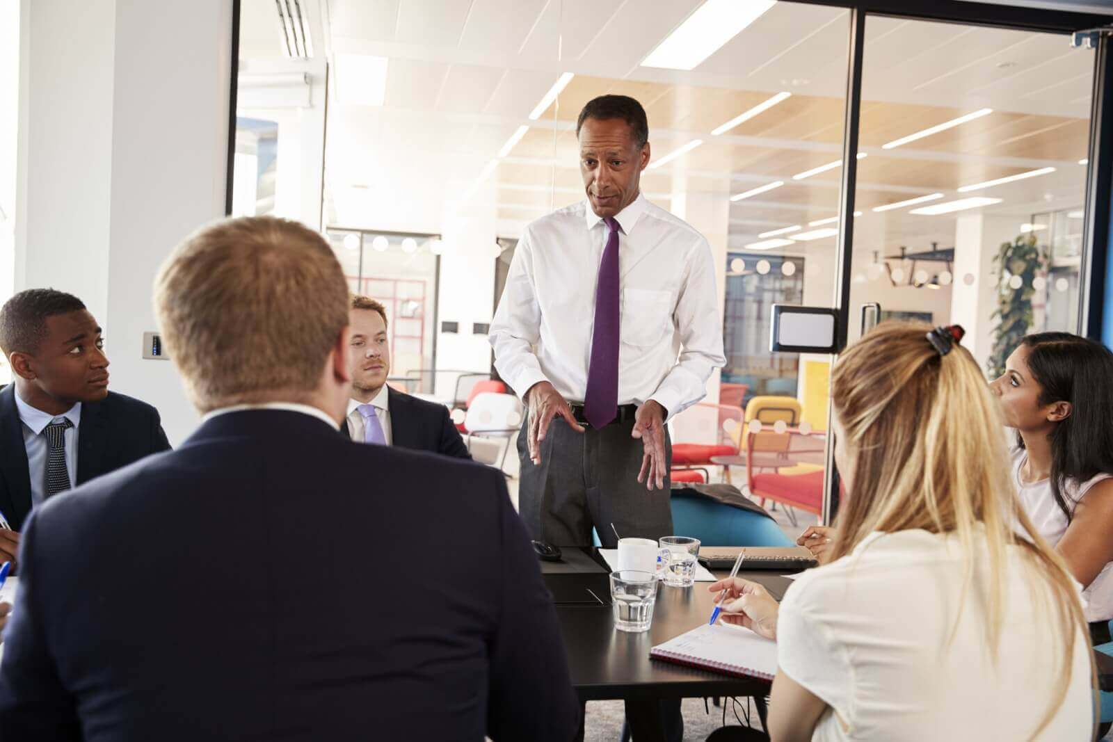 black male manager stands talking at a business me P2R9ZEU scaled 1