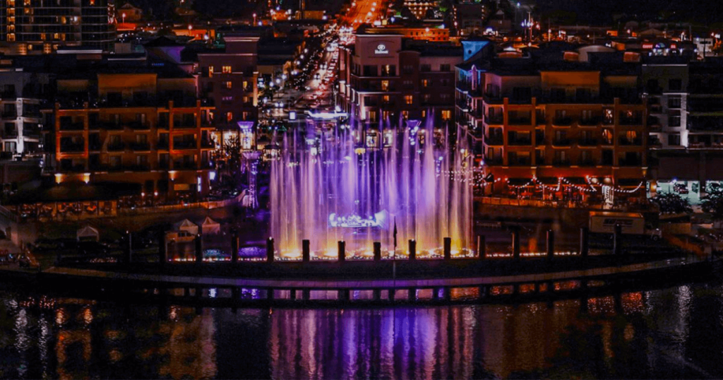 A vibrant, illuminated water fountain display at night in front of city buildings