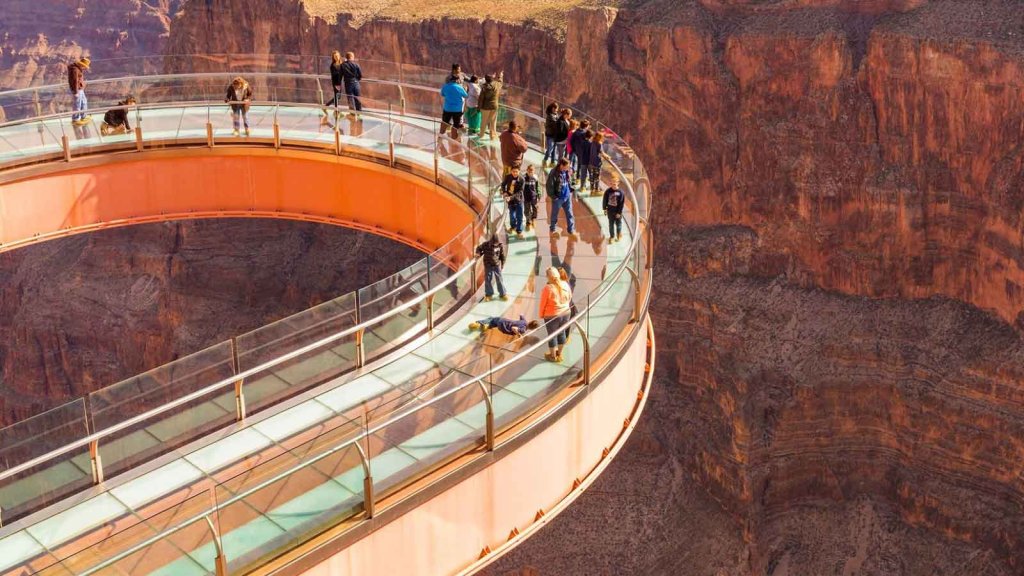 Tourists walk on a horseshoe-shaped glass skywalk overlooking a deep canyon