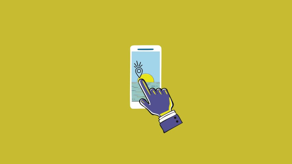 A hand touching a smartphone screen displaying a location pin over a sunset