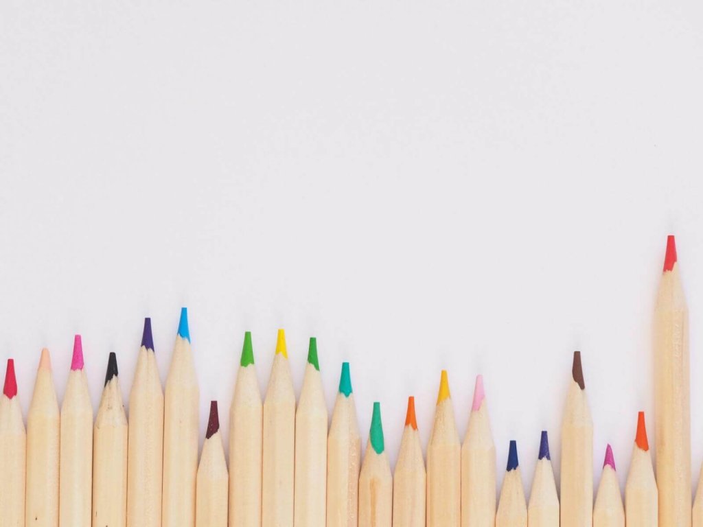 A row of colorful sharpened pencils standing against a plain white background
