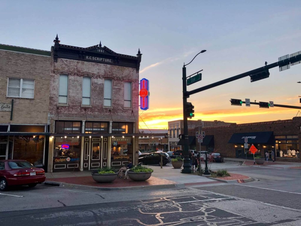 A historic brick building with a neon sign at sunset in a small town
