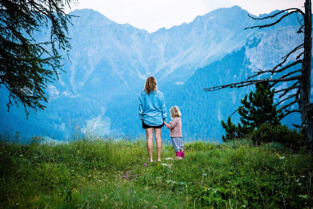 A woman and a young child holding hands while looking at mountain scenery