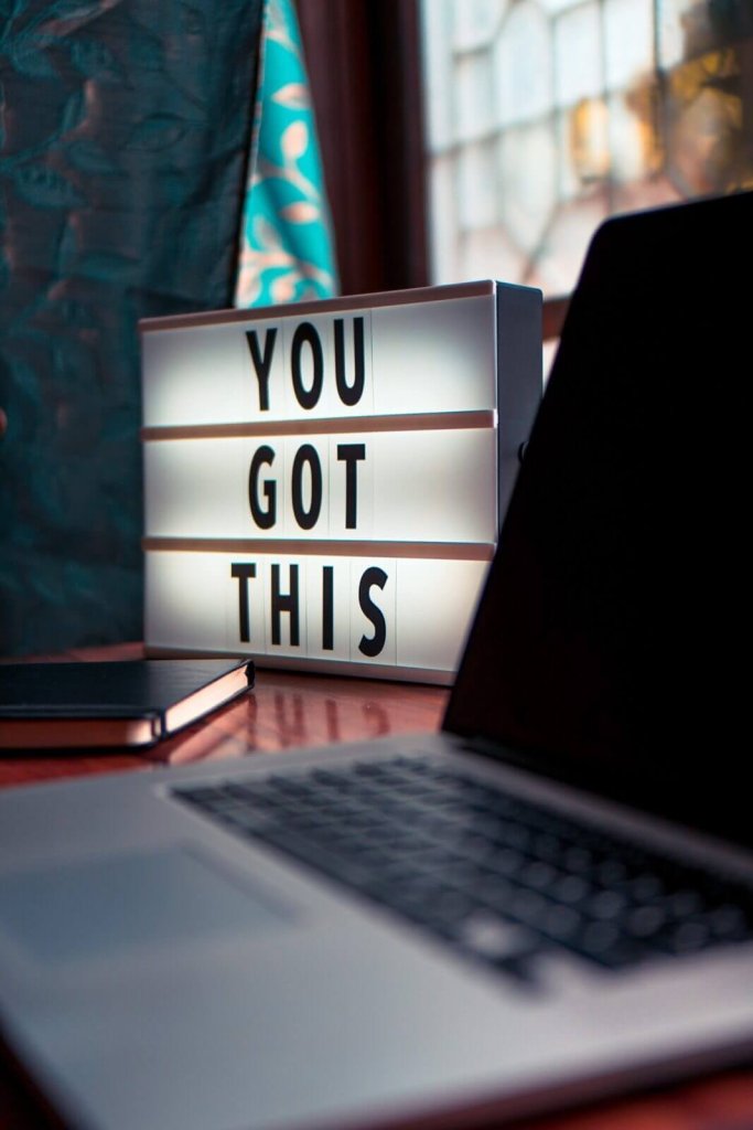 A lightbox with the words You Got This sits on a desk near a laptop