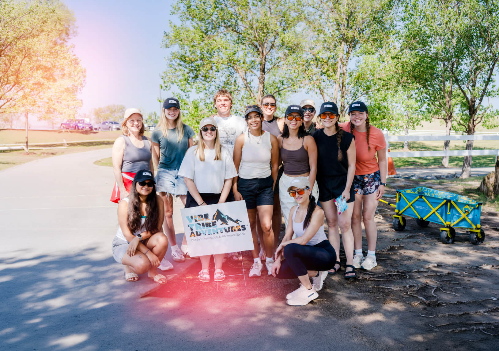 A group of people posing with a Vibe Tribe Adventures sign outdoors