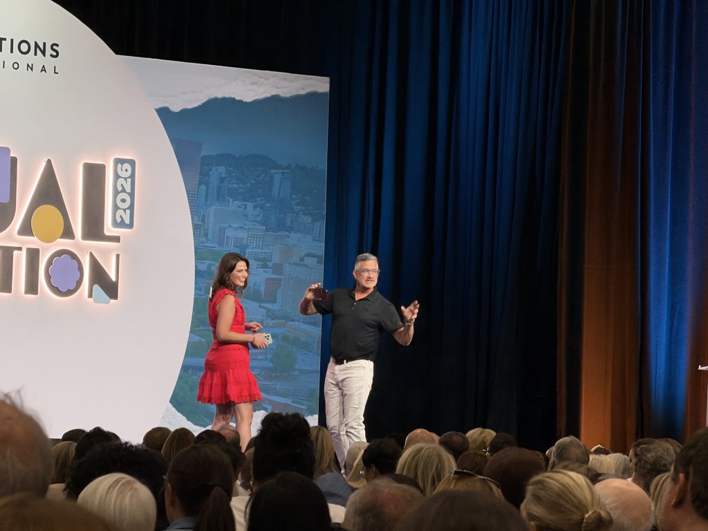 Two presenters on stage in front of a large audience at a conference
