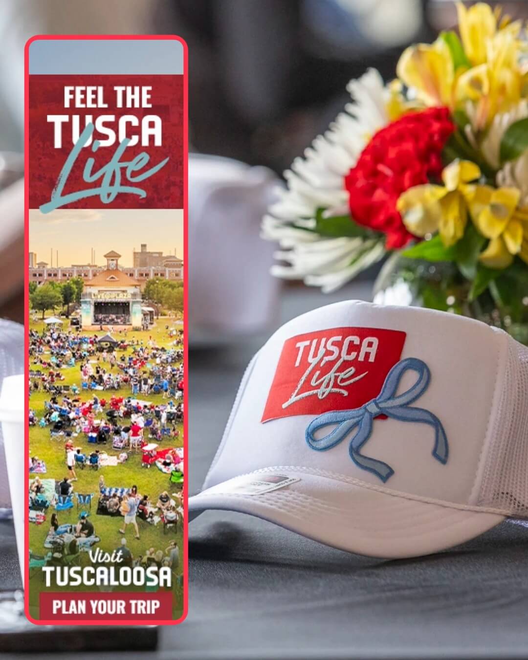 A white trucker hat with a Tusca Life logo sits next to a flower bouquet