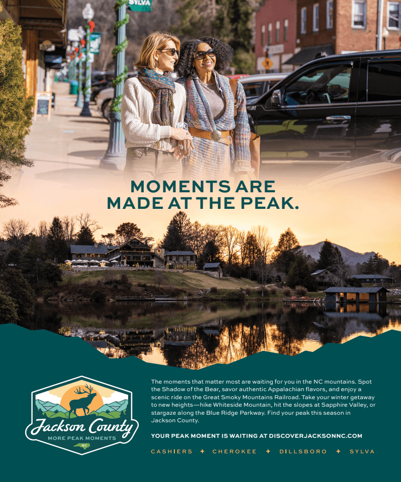 Two women walk down a street, above a lake with houses and mountains