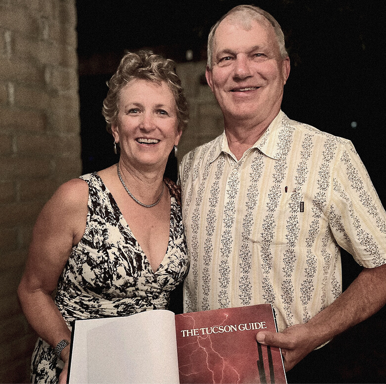 A smiling couple holds an open book titled "The Tucson Guide."